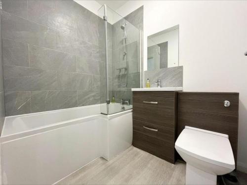 a bathroom with a tub and a toilet and a sink at Premier Serviced Apartmetns oldham road Manchester in Manchester