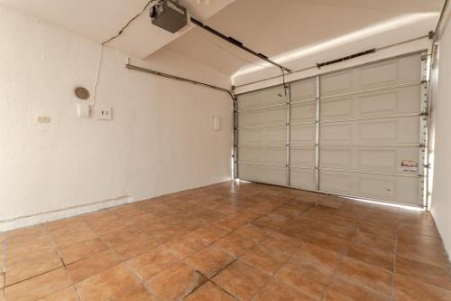 an empty garage with white doors and a tile floor at Comfortable and family house Eva Pet friendly in Chihuahua