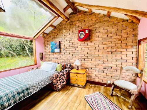 a bedroom with a bed and a brick wall at Varsovia, casa de madera biblioteca in Guatavita