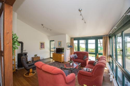 Il comprend un salon doté de fauteuils rouges et d'une télévision. dans l'établissement Haus Kerstin am Jabeler See, à Jabel