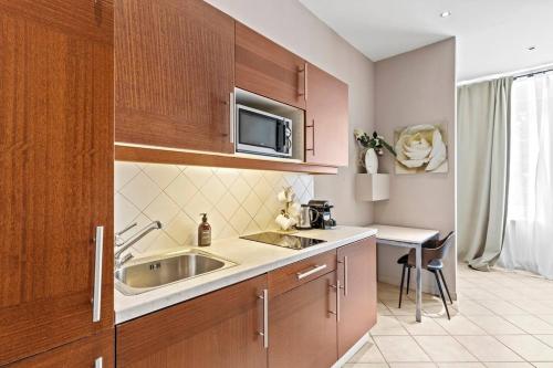une petite cuisine avec un évier et un micro-ondes dans l'établissement Augarten Suites I 5 min to Metro I 10 Min to City, à Vienne