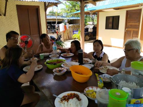 a group of people sitting around a table eating food at Hondelz Budget Homestay in Busuanga
