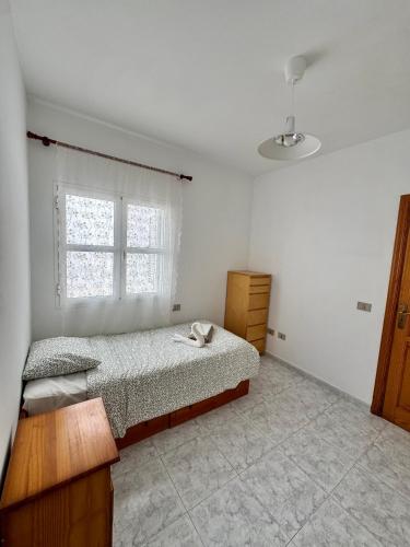 a white bedroom with a bed and a window at Royal Home in Arrecife