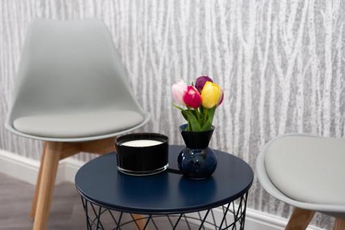 a blue table with a vase with flowers on it at Diana Hotel London Wembley in London