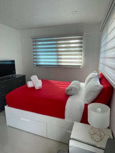 a bedroom with a red bed and a window at Studio close to airport in Dania Beach