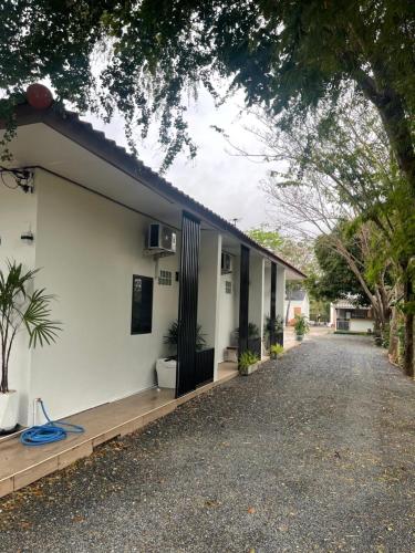 a house with white walls and a driveway at นาราชา มินิมอล รีสอร์ท in Sathani Nong Pling