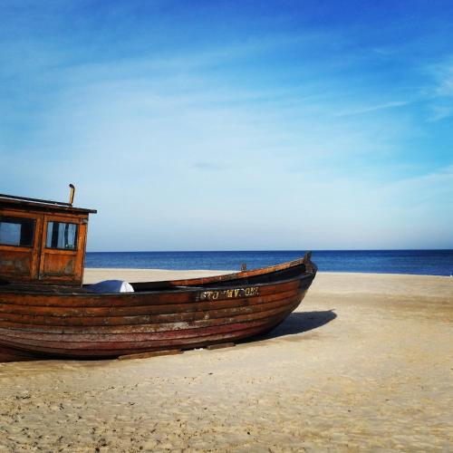 a wooden boat sitting on a sandy beach at Strandperle App 10 in Neuhaus