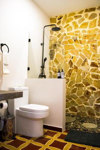 a bathroom with a toilet and a stone wall at Casa Zoé Hotel Boutique in Villeta