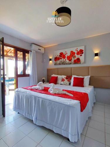a bedroom with a large white bed with red pillows at AREIA DE TAPERAPUAN - 200 MTS da PRAIA - ORLA NORTE in Porto Seguro