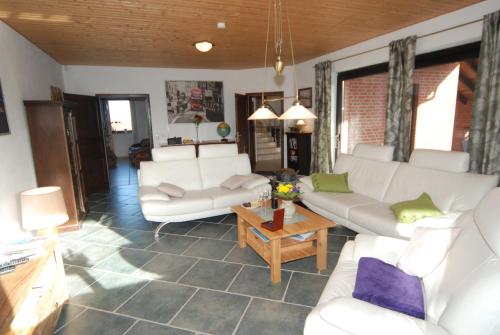 a living room with white couches and a table at Ferienwohnung Muschel in Heiligenhafen