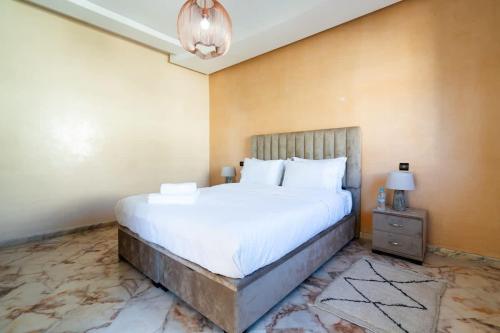 a bedroom with a large white bed and a lamp at Maison avec Piscine Proche Plage in El Harhoura