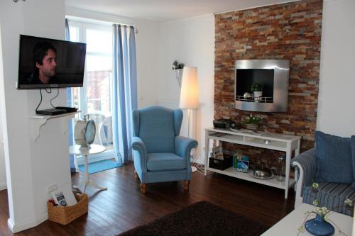 ein Wohnzimmer mit einem TV und einem blauen Stuhl in der Unterkunft LANDHAUS AM HAFEN im OG in Heiligenhafen