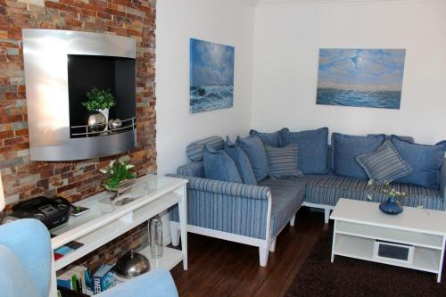 ein Wohnzimmer mit einem blauen Sofa und einem Fernseher in der Unterkunft LANDHAUS AM HAFEN im OG in Heiligenhafen