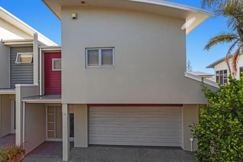 a white house with a garage at Sunny Daze - Ohope Beach Holiday Home in Ohope Beach