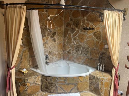 a bath tub in a stone bathroom with curtains at Magical Malewa Retreat in Naivasha