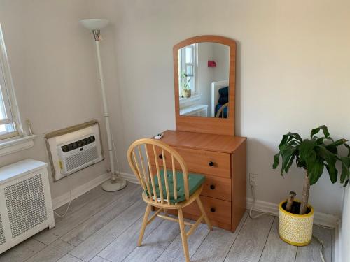 a wooden dresser with a mirror and a chair at Cheerful 2 BED ROOMS Apartment in heart of Queens in Jackson Heights