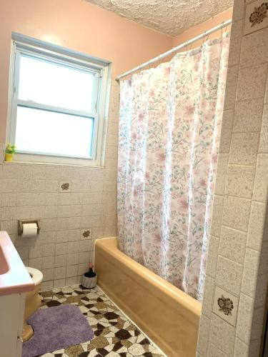 a bathroom with a tub and a shower curtain at Cheerful 2 BED ROOMS Apartment in heart of Queens in Jackson Heights