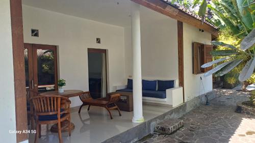 a porch of a house with a table and chairs at Si Pitung Village in Gili Air
