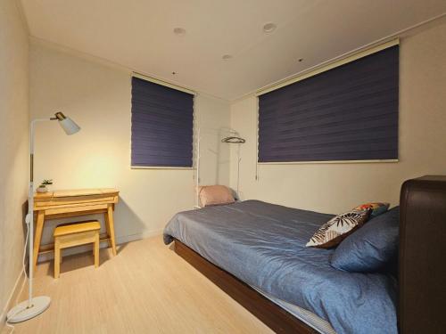 a bedroom with a bed and a desk with two windows at 서울 더블역세권 감성 하우스 in Seoul