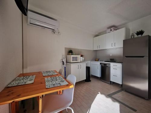 - une cuisine avec des placards blancs, une table et un réfrigérateur dans l'établissement Studio 4 personnes en bord de mer au Lavandou avec parking - FR-1-803-89, au Lavandou