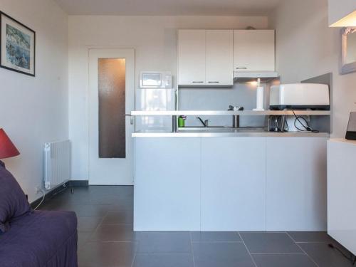 une cuisine avec des armoires blanches et un canapé dans une pièce dans l'établissement Studio cabine au Lavandou, jardin privé, plage accessible - FR-1-803-83, au Lavandou