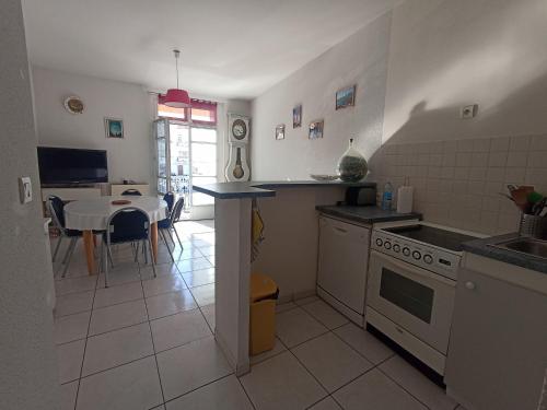 Il comprend une cuisine équipée d'une cuisinière et une salle à manger avec une table. dans l'établissement Maison 3 chambres, 6 couchages, proche gare, Sète, WIFI - FR-1-338-605, à Sète