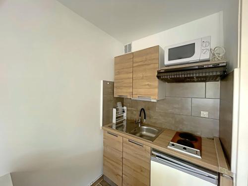 une petite cuisine avec un évier et un micro-ondes dans l'établissement Appartement 4 pers avec cour sud aux Saintes-Maries-de-la-Mer - FR-1-475-179, à Saintes-Maries-de-la-Mer