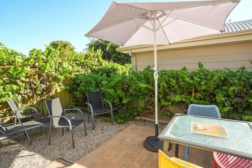 a table and chairs with an umbrella on a patio at McLaren Vale Studio Apartments in McLaren Vale