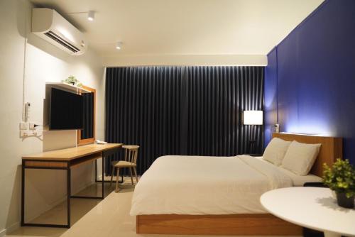 a bedroom with a bed and a desk and a television at The View Residence in Bangkok