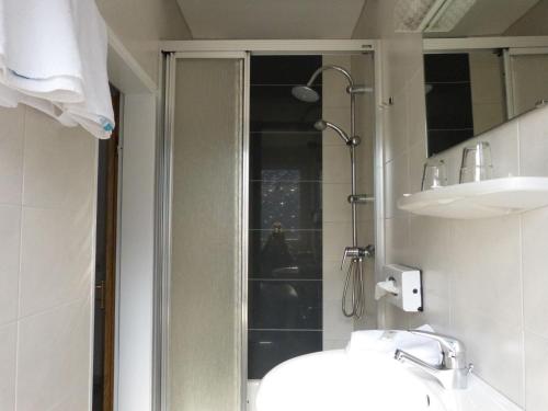 a bathroom with a shower and a sink and a mirror at Hotel Brandaris in Langeoog