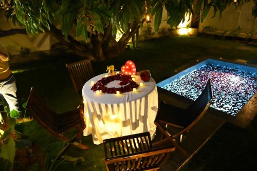 a table with a cake on it next to a pool at Aura Farms - Private Pool Cottages in Rāmanagaram