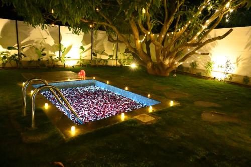 a pool with lights in a yard at night at Aura Farms - Private Pool Cottages in Rāmanagaram