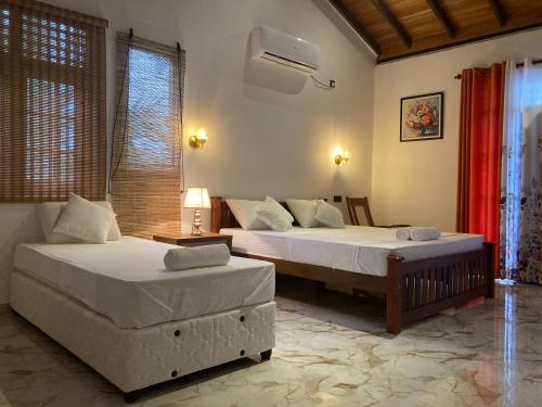 a bedroom with two beds and a table and a bedskirts at Margosa villa in Tangalle