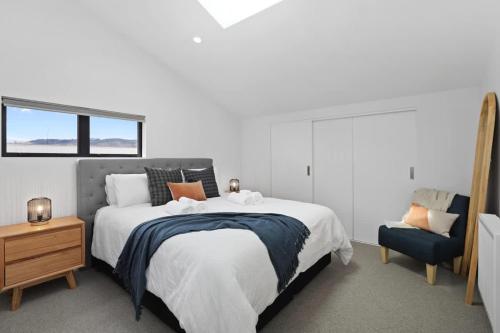 a bedroom with a large bed and a chair at Serenity on Sophia in Rotorua