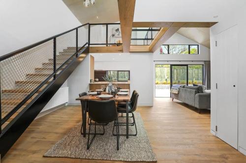 a living room with a table and a staircase at Serenity on Sophia in Rotorua