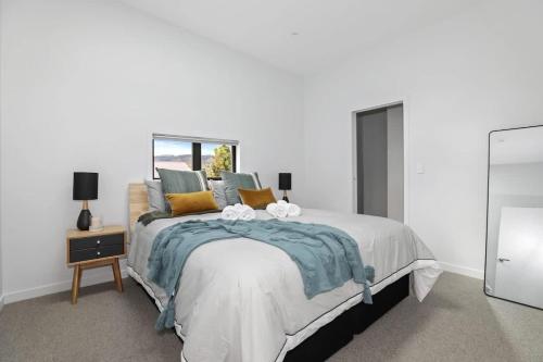a white bedroom with a large bed and a table at The Sanctuary in Rotorua