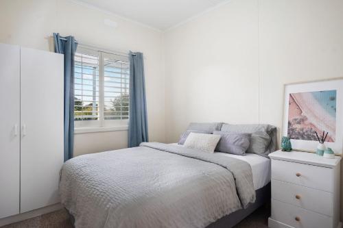 a white bedroom with a bed and a window at The Blue Bunyip - 3 Bunyip St in Goolwa South