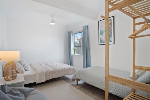 a white bedroom with two beds and a ladder at The Blue Bunyip - 3 Bunyip St in Goolwa South