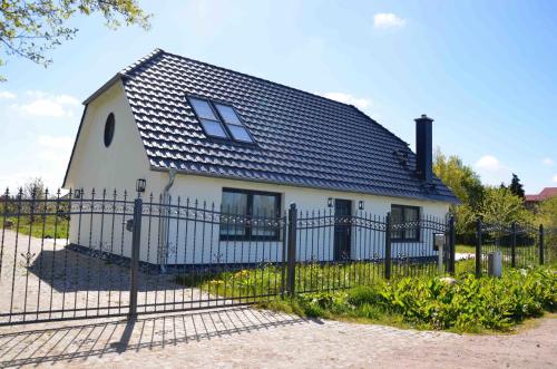 a white house with a black roof behind a fence at Landhaus in Wiek auf Rügen 