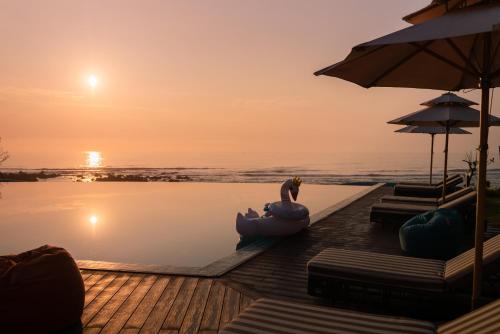 a woman sitting in a pool next to a body of water at Edensee Kega Beach Resort in Ke Ga