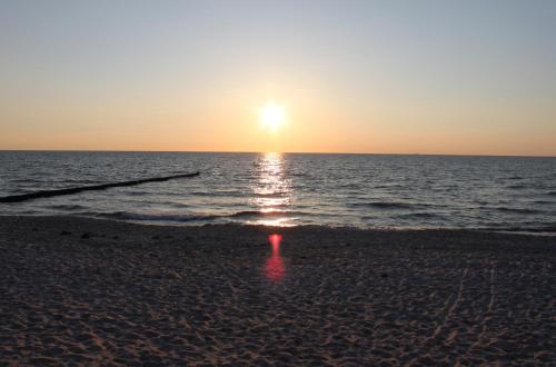 a sunset on a beach with the ocean at "Koppeldeich" in Dierhagen