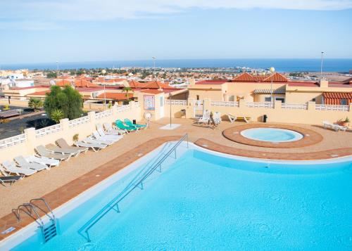 een groot zwembad met stoelen en een gebouw bij The Blue Tajinaste in Caleta De Fuste
