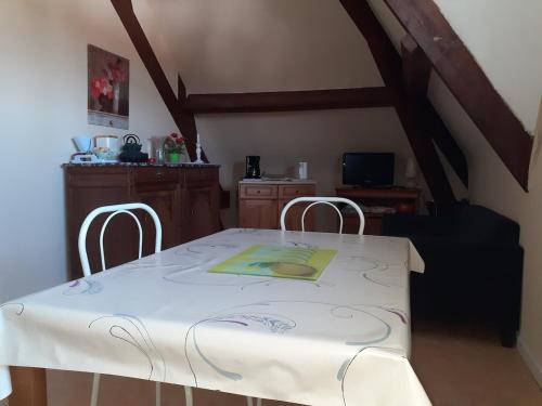 une table à manger avec deux chaises et un tissu de table blanc dans l'établissement Villa Beauregard La Roche Posay, à La Roche-Posay