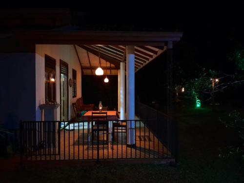 a porch at night with a table and chairs at Lime House in Udawalawe
