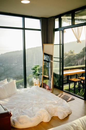a large bed in a room with large windows at ภูสิริ โฮมสเตย์ in Ban Thung Phan Ha