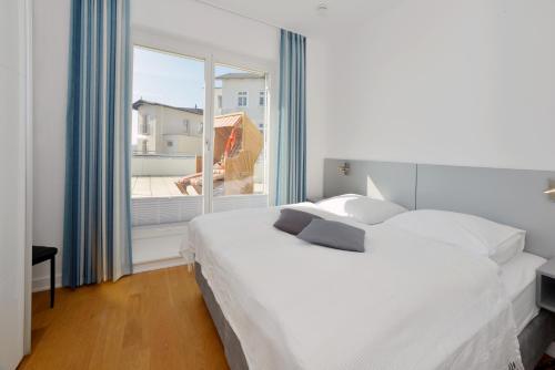 a bedroom with a white bed and a large window at Suite Meersinn in Sassnitz