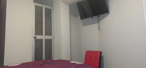 a room with a red chair and a tv on the wall at Hotel San Miguel in San Miguel