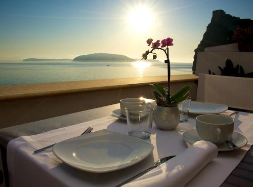 a table with plates and cups and a view of the ocean at Villa Lieta in Ischia