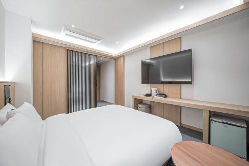 a hotel room with a bed and a flat screen tv at Hound Hotel DaeGu in Daegu