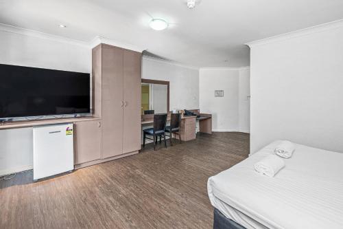 a hotel room with a bed and a flat screen tv at Diplomat Hotel Alice Springs in Alice Springs